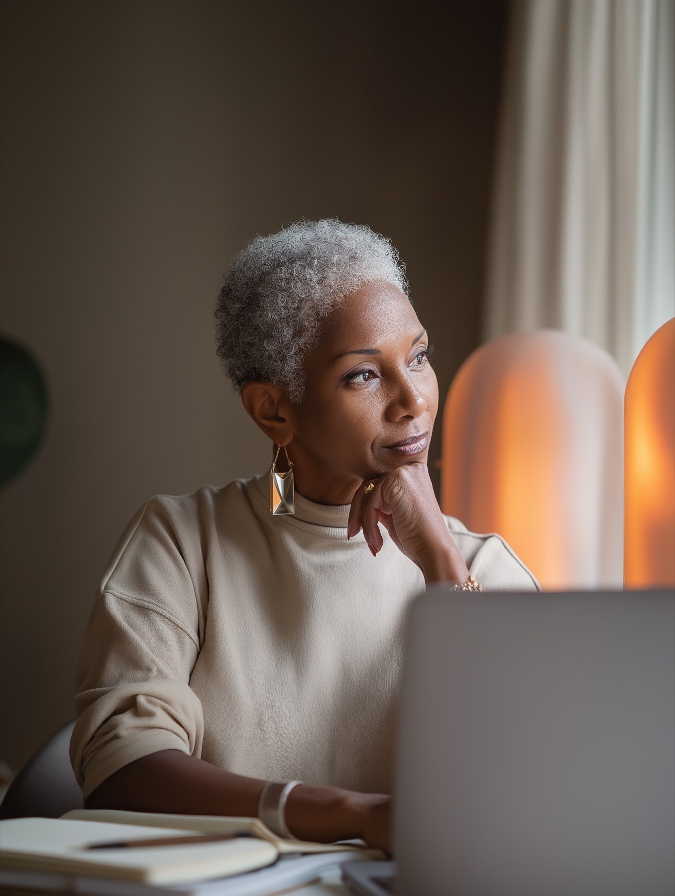 Woman at her desk in warm light, considering her next step — Her Path at Kassy Wellness